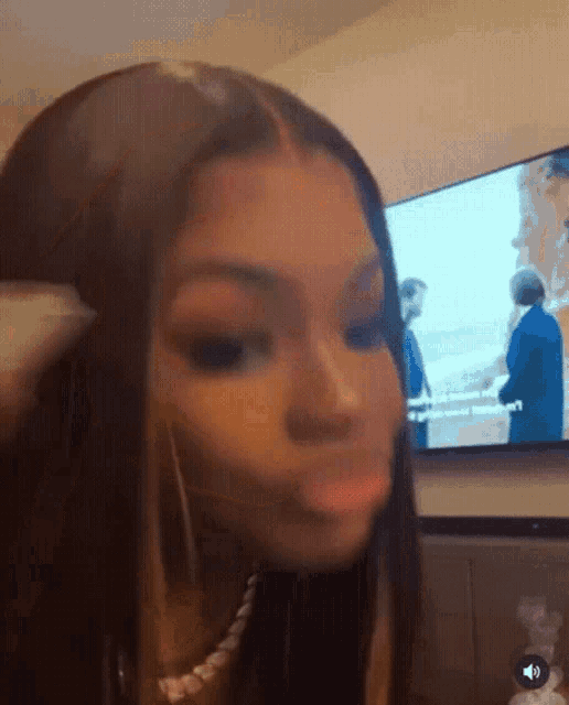 a woman is making a funny face in front of a tv .