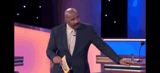 a man in a suit and tie is holding a piece of paper that says ' who wants to be a millionaire '
