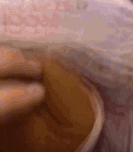 a close up of a cup of coffee with a pink blanket in the background