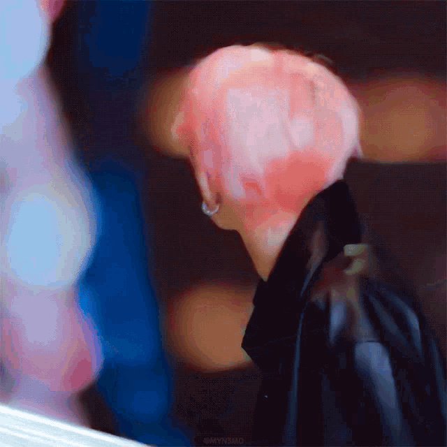 a person with pink hair is wearing a black jacket .