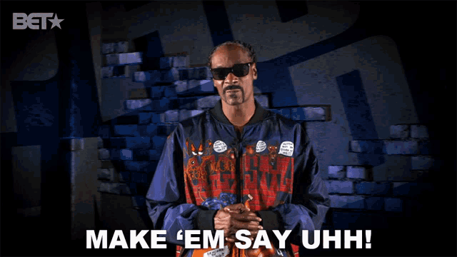 snoop dogg is standing in front of a brick wall and says make ' em say uhh '