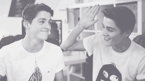 two boys are giving each other a high five and one of them has a shirt with a penguin on it