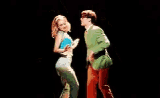 a man and a woman are dancing together on a stage . the man is wearing a green jacket .