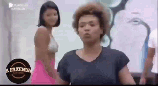 a woman in a pink skirt is standing next to another woman in a white bra .