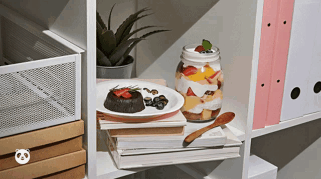 a stack of books with a plate of food and a jar of fruit on a shelf