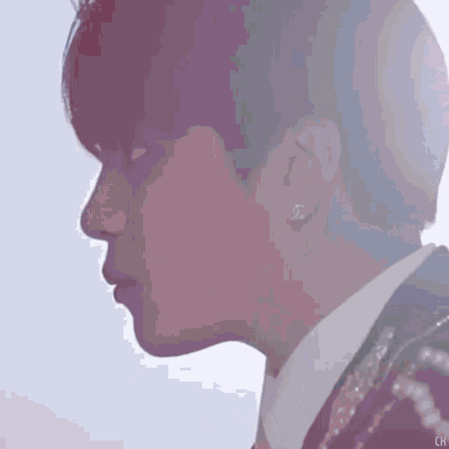 a close up of a person 's face wearing earrings and a suit .