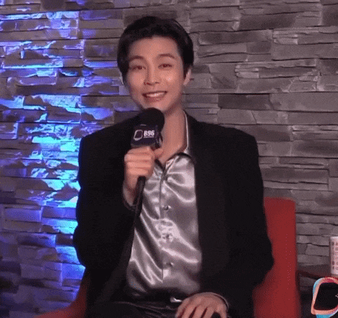 a man in a suit is holding a microphone and smiling .