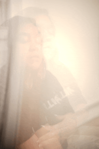 a blurry photo of a woman wearing a black shirt that says l.i.a.l.a.