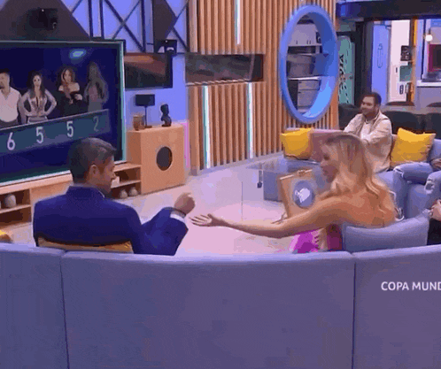a group of people are sitting on a couch in a living room watching a television .