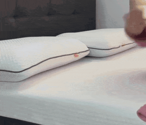 a person is laying on a bed with two pillows