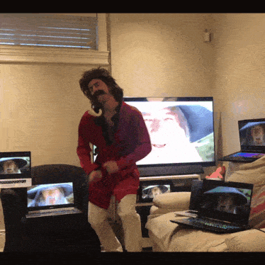 a man in a red jacket is dancing in front of a tv screen
