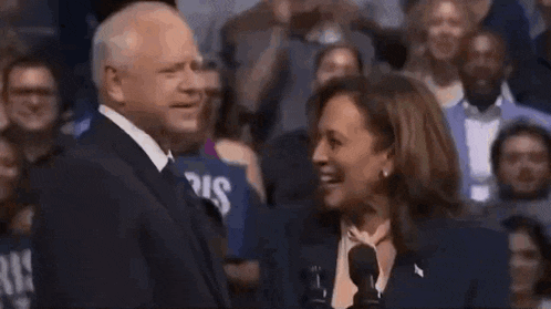 a man and a woman are laughing together in front of a crowd of people .