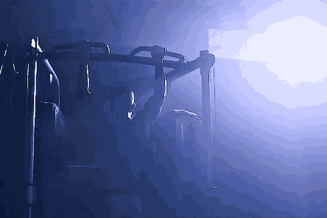 a man is doing pull ups on a bar in a dark room