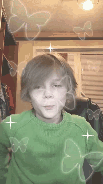 a young boy in a green sweater is surrounded by butterflies and stars