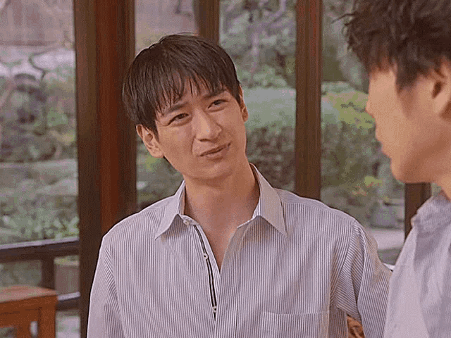 a man in a striped shirt talks to another man in a purple shirt
