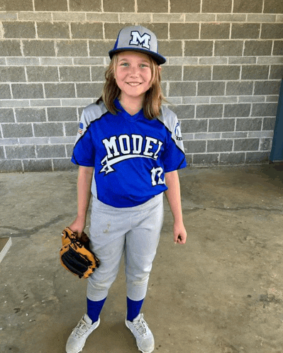 a young girl wearing a model baseball uniform holds a glove