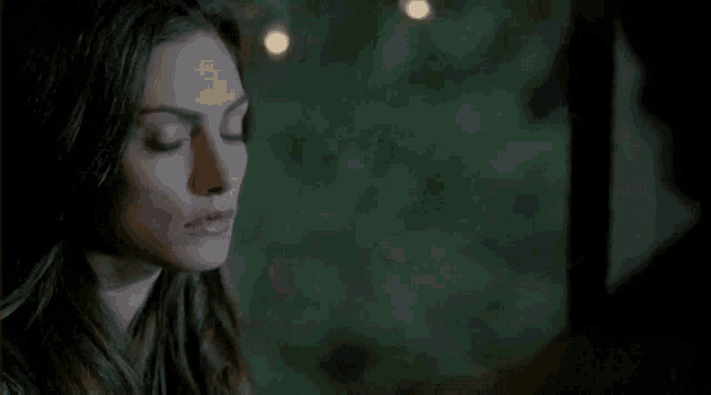a close up of a woman 's face in a dark room with lights behind her .