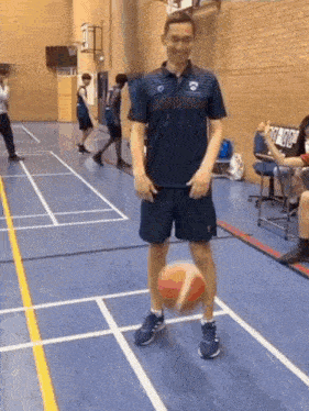 a man in a blue shirt is holding a basketball in a gym