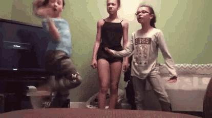 a boy and two girls are jumping in the air in a room .