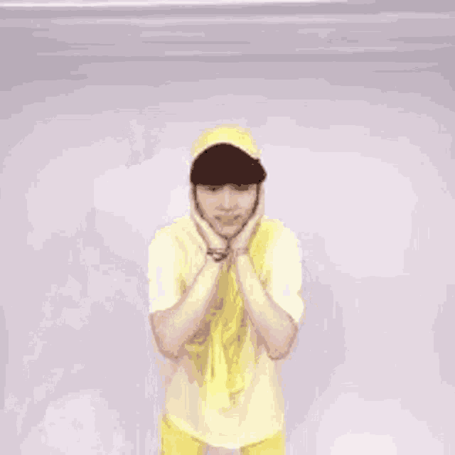 a young man wearing a yellow shirt and a yellow hat is standing in a room .
