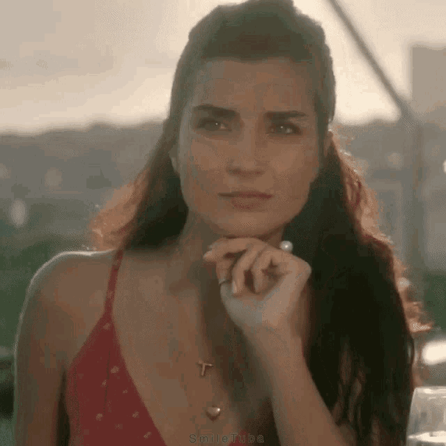 a woman wearing a red top and a necklace with a cross on it