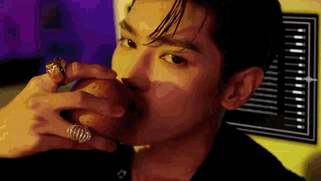 a close up of a man eating an apple with rings on his fingers