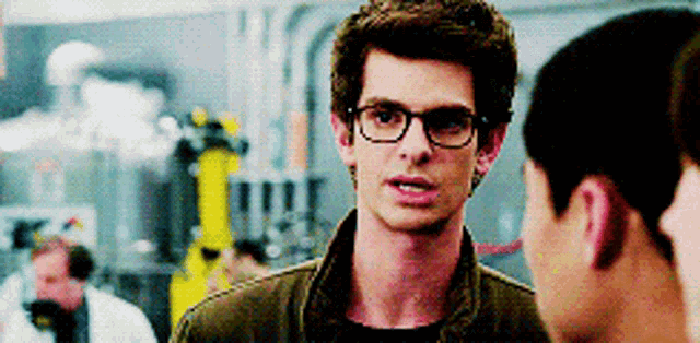 a man wearing glasses is talking to two other men