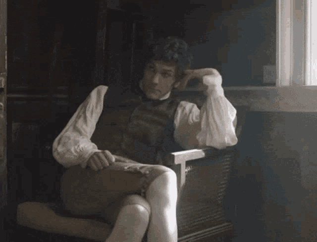 a man in a vest and white socks is sitting in a chair
