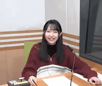 a woman is sitting at a table in front of a microphone .