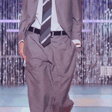a man in a suit and tie is walking on a red carpet