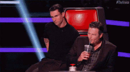 a man in a suit is sitting in a chair next to a man in a plaid shirt .