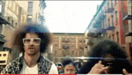 a man with an afro wearing sunglasses stands in front of a street