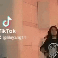a woman wearing a black shirt with a cat on it is standing in front of a wall .