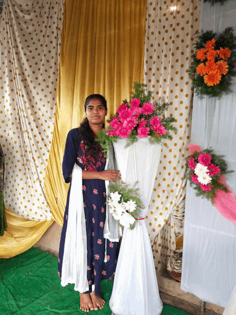 a woman in a blue dress holds a vase of flowers