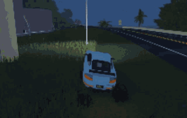 a blue car is driving down a highway at night with a yellow sign that says ' yield ' on it