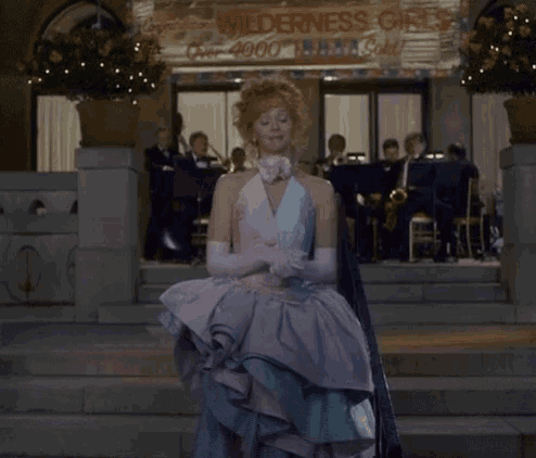a woman in a pink dress is standing in front of a sign that says wilderness girls
