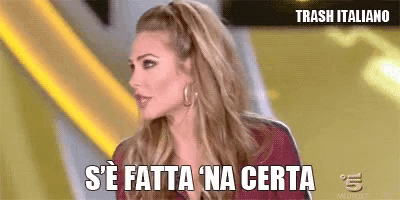 a woman is sitting on a stage with the words s ' e fatta na certa written on her face .