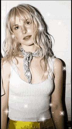 a blonde woman wearing a white tank top and a bandana around her neck .