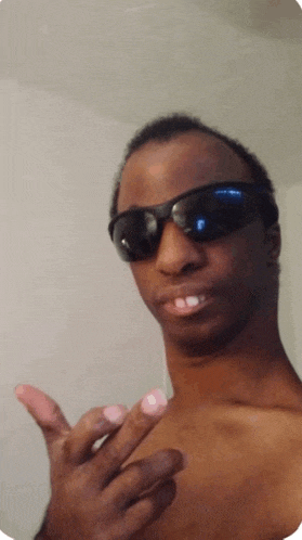 a shirtless man wearing sunglasses makes a funny face