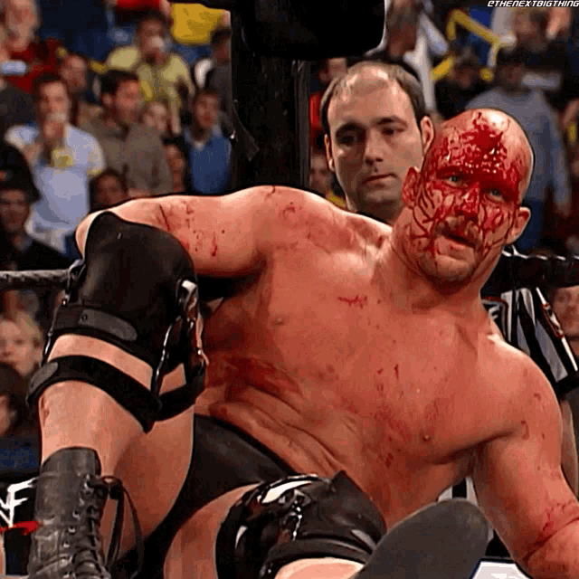 a wrestler with blood on his face is being lifted by a referee