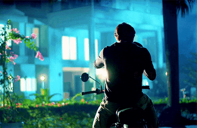 a man is riding a motorcycle in front of a large house