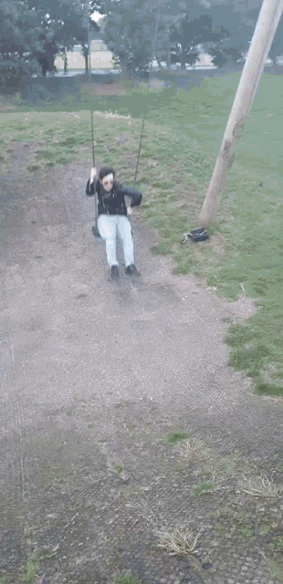 a person swinging on a wooden swing in a field