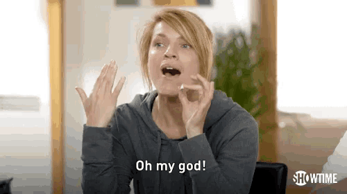 a woman is sitting at a table with her hands in the air and making a funny face .