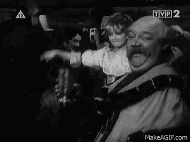 a black and white photo of a group of people dancing in a dark room .