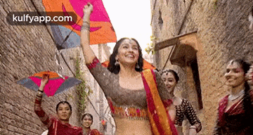 a woman is holding a kite in her hand while dancing with other women .