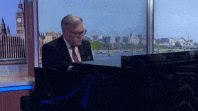 a man in a suit and tie is sitting at a desk in front of a window