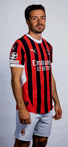 a man wearing a red and black striped shirt with emirates fly better written on it
