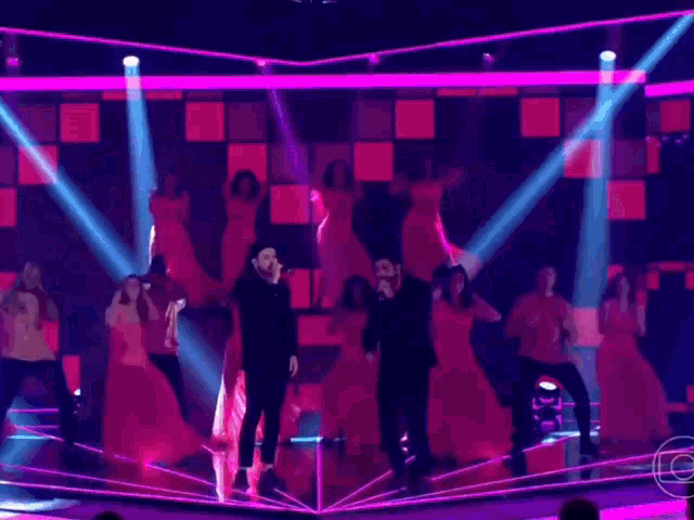 a group of people are dancing on a stage with a microphone