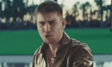 a man in a leather jacket is standing in front of a green screen .