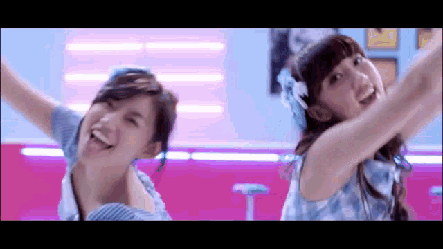 two girls are dancing together in a room with their arms outstretched